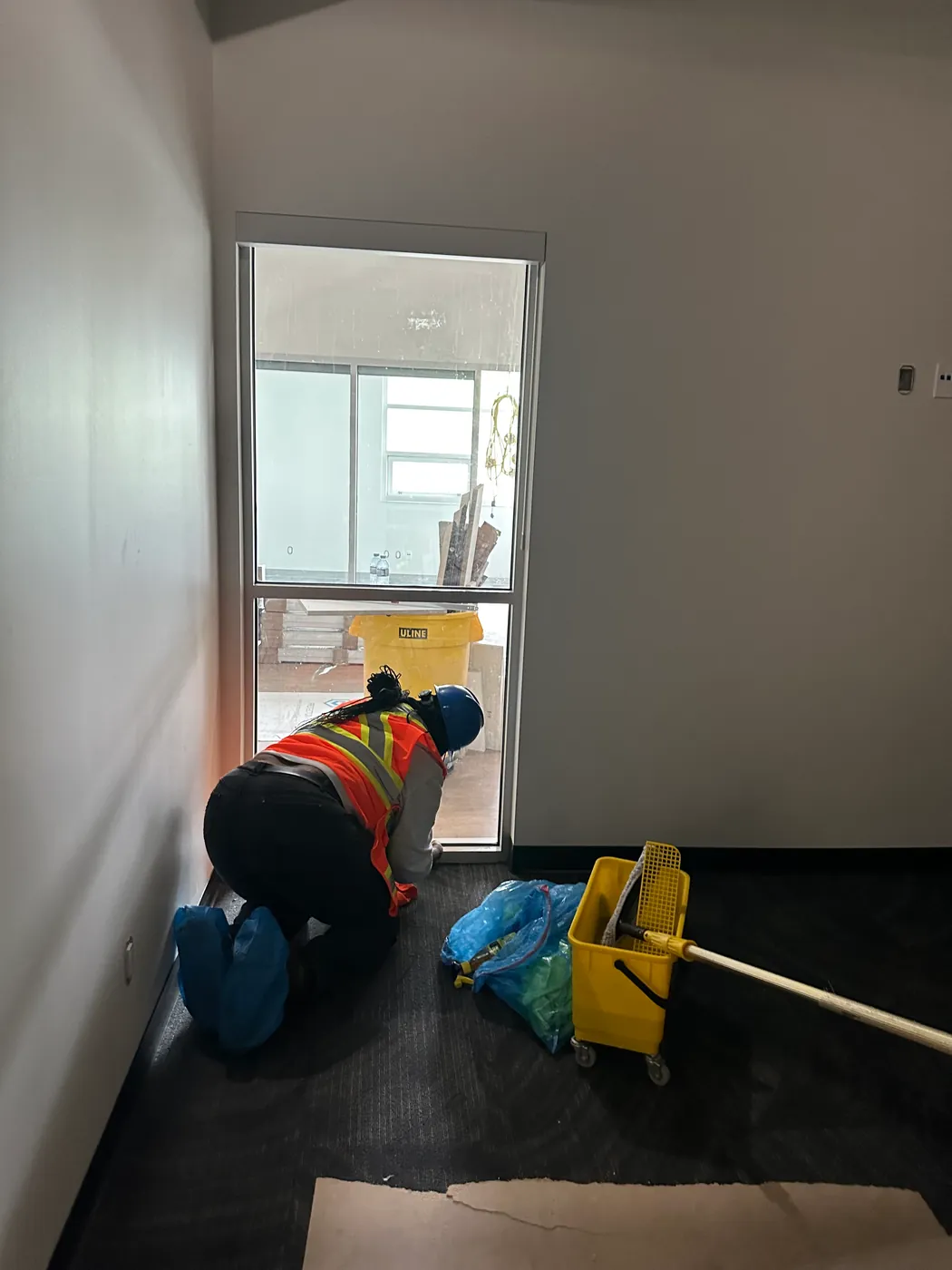 Kanians technician detail-cleaning a commercial unit with a mop and bucket during post-construction cleanup