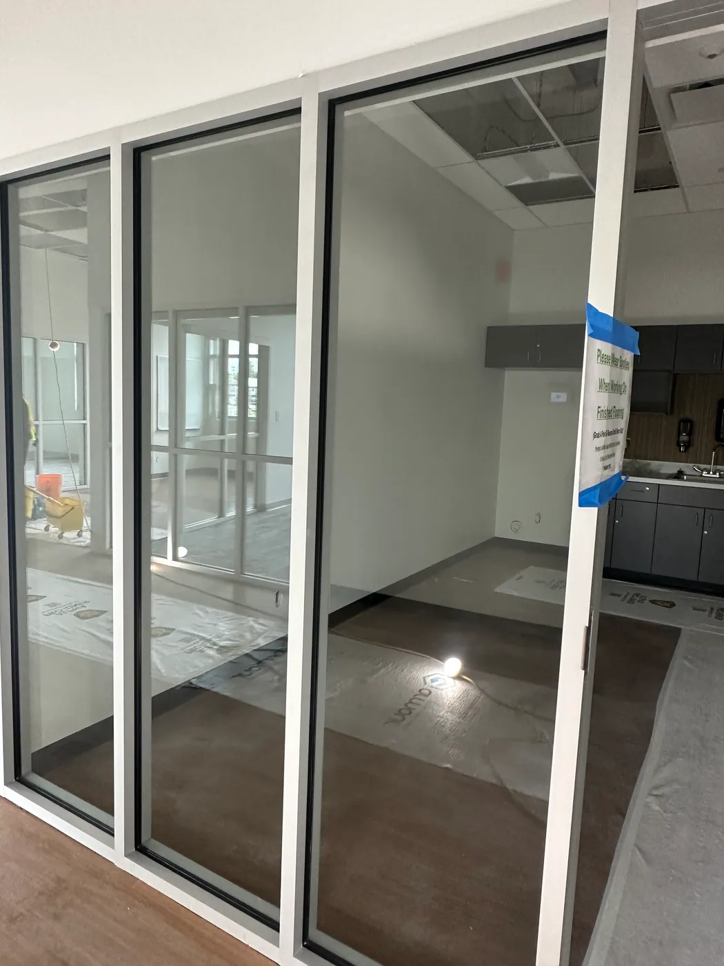 Newly constructed glass-walled offices with protective floor film during a post-construction clean